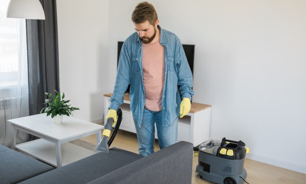 Curățare canapea cu aspirator profesional în sufragerie.