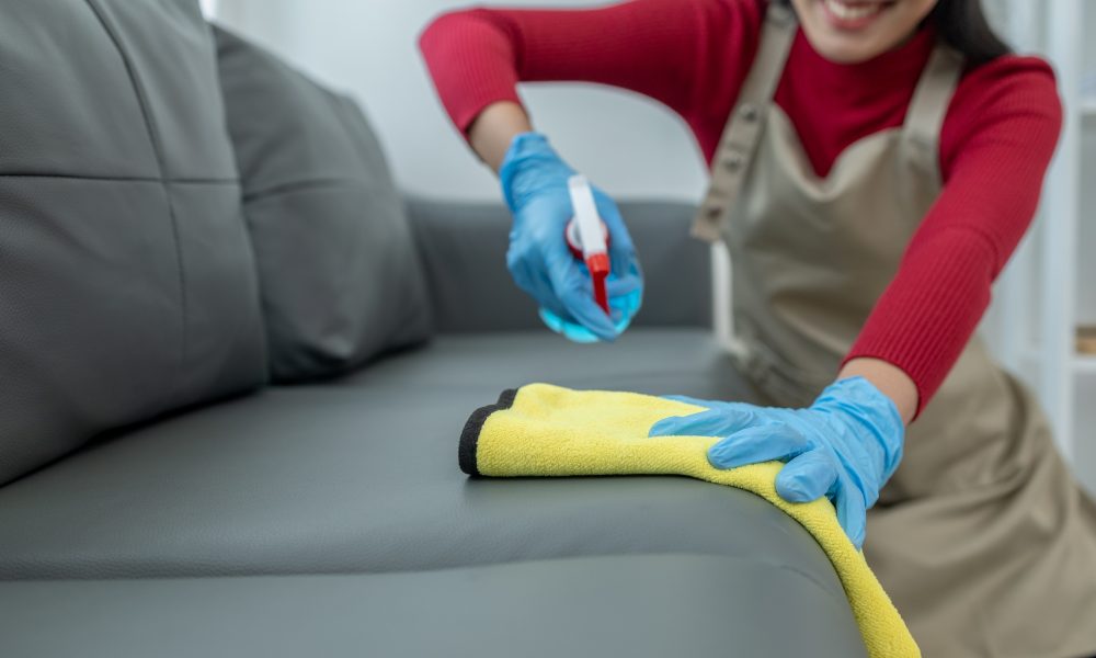 Persoană curăță canapea cu soluție și cârpă